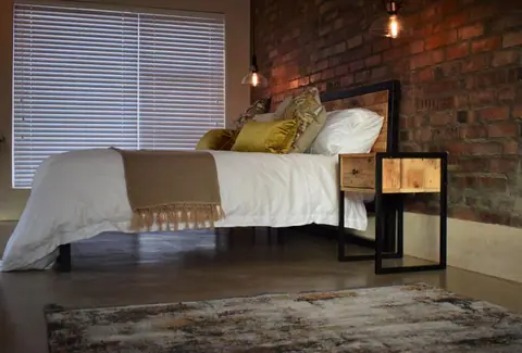 King bed with gold cushions and a brick feature wall