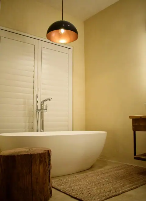 Free-standing bath under a copper pendant light