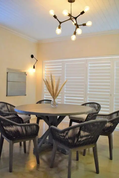 Round dining table with woven chairs under a modern chandelier
