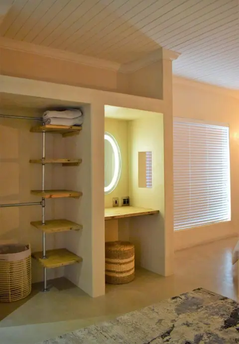 Dressing area with open shelving and a lit mirror