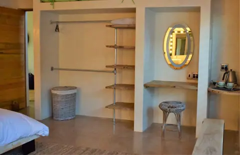 Dressing area with open shelving and a round lit mirror