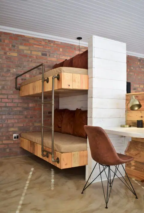 Built-in bunk bed and desk against a brick wall